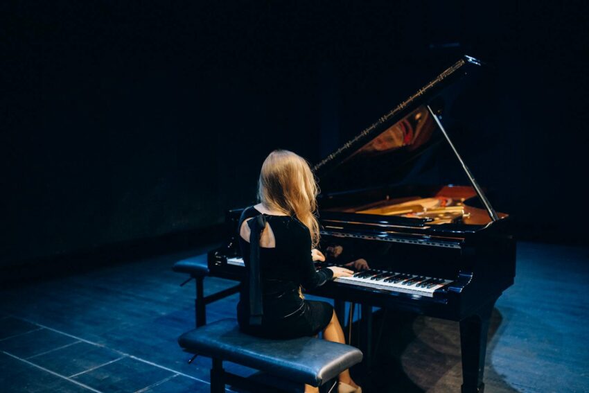 Woman in Black Long Sleeve Dress Playing Piano