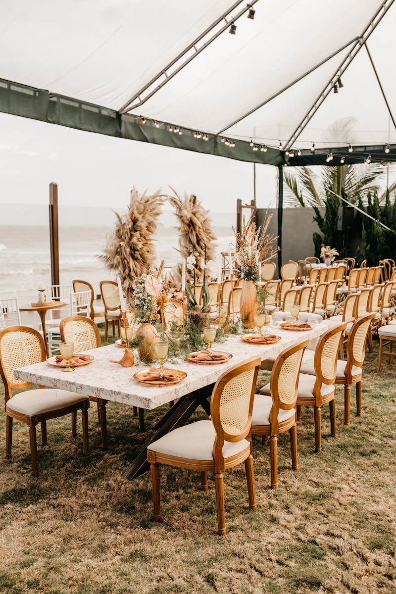 Stylish outdoor dining setup on a beachfront, featuring elegant decor and natural elements.